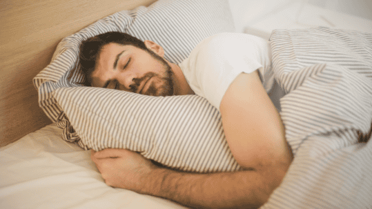 Man asleep in bed, illustrating the risks of sleeping in contact lenses