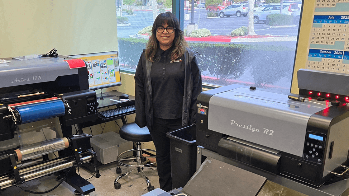 Print production assistant operating a four-color offset printing press in a modern print facility.