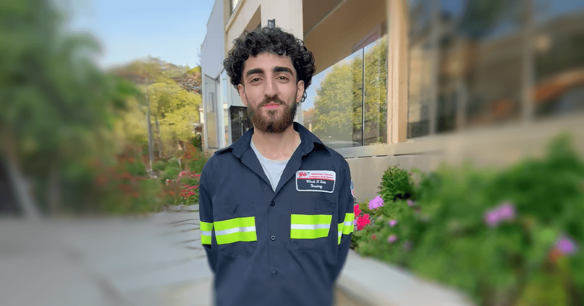 Sevan smiling in a work uniform with high-visibility stripes, representing a hands-on career in the automotive and service trades.