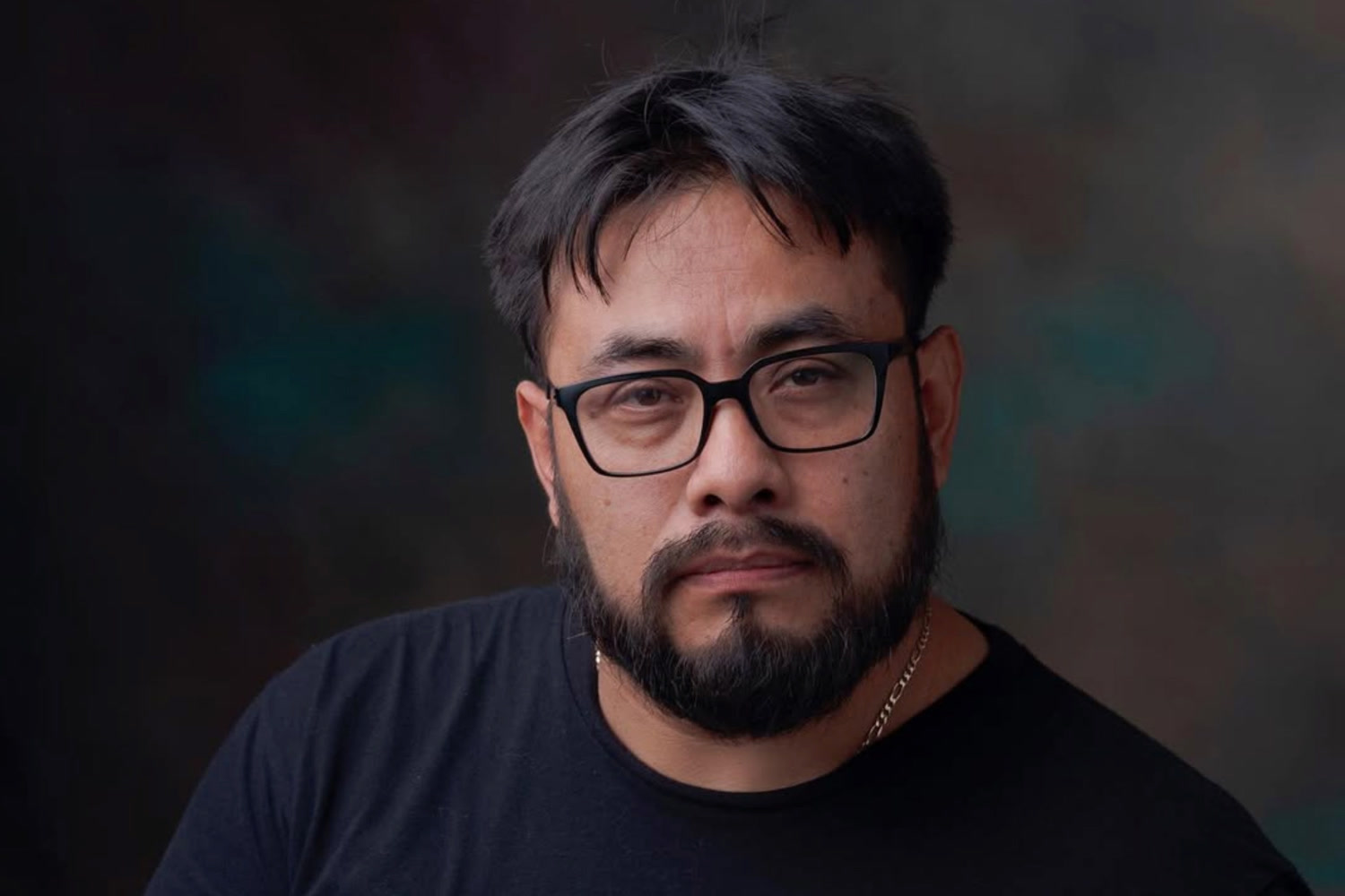 Indy Ortiz, photographer and printer, wearing glasses in a studio portrait