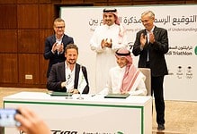 Sponsorship agreement signing at a triathlon event in Saudi Arabia, with officials and representatives celebrating the partnership in a formal setting.