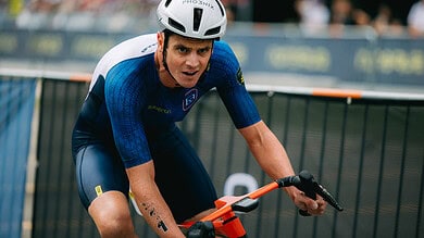 Male triathlon athlete in blue cycling gear and helmet riding a bike during a race, demonstrating endurance and focus at a competitive triathlon event.