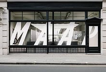 Contemporary office storefront featuring large white M A P letters on glass windows, with a sleek black frame and urban street setting.