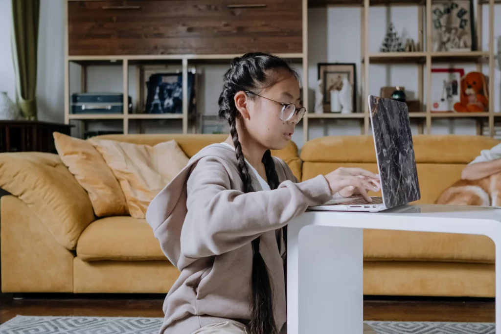 a young woman sitting on the carpet while using her laptop