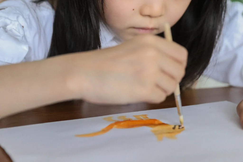 serious asian kid painting with aquarelle in art studio