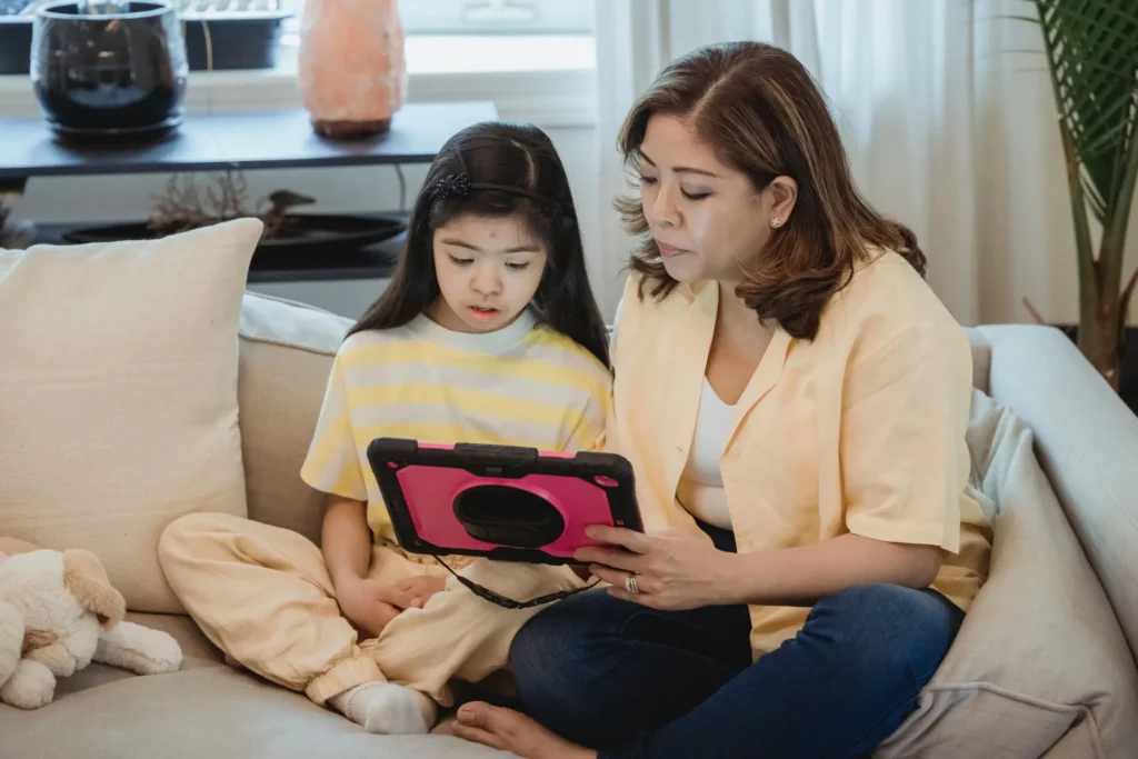 woman teaching female child with a tablet