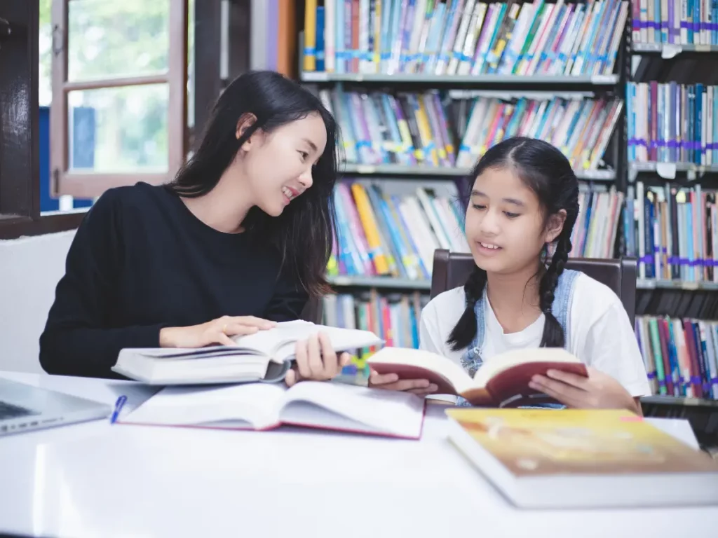 a tutor and a young student studying in a library | tuitioncentre sg