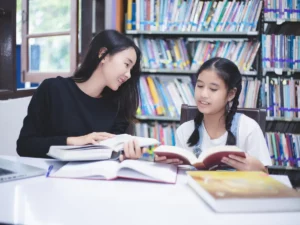 a tutor and a young student studying in a library | tuitioncentre sg