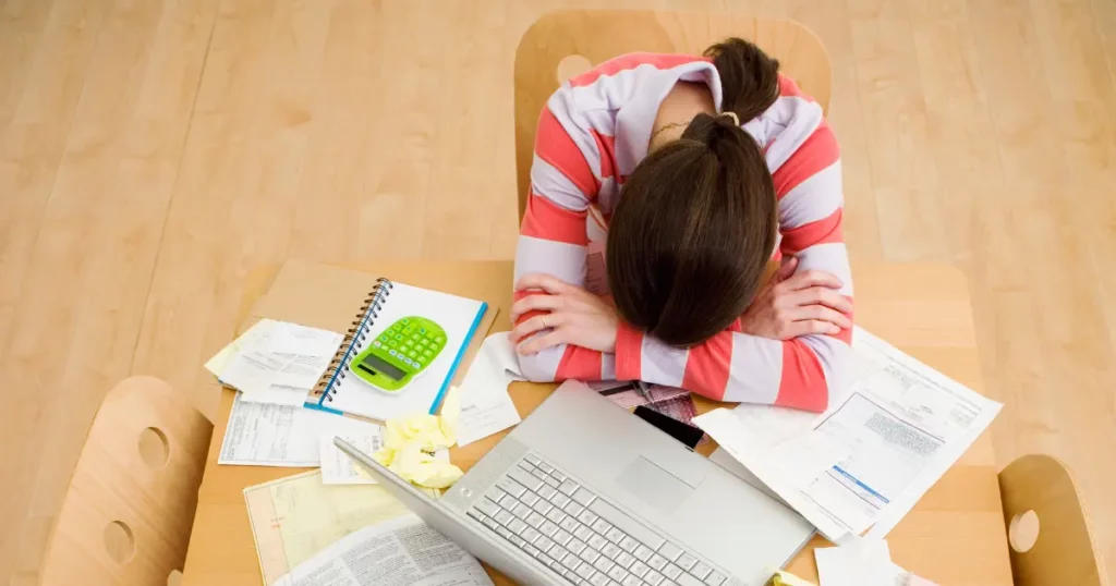 a person sitting at a table with a laptop and papers | tuitioncentre sg