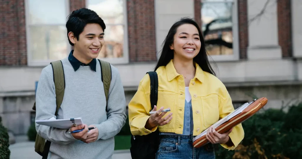 two students walking on the sidewalk holding folders | tuitioncentre sg