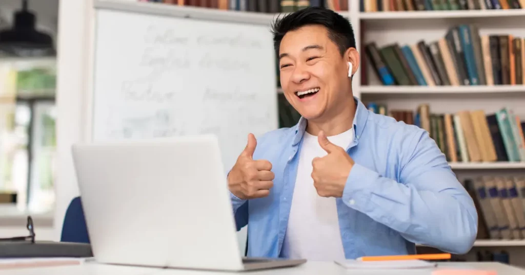 a tutor sitting in front of a laptop and giving a thumbs up | tuitioncentre sg