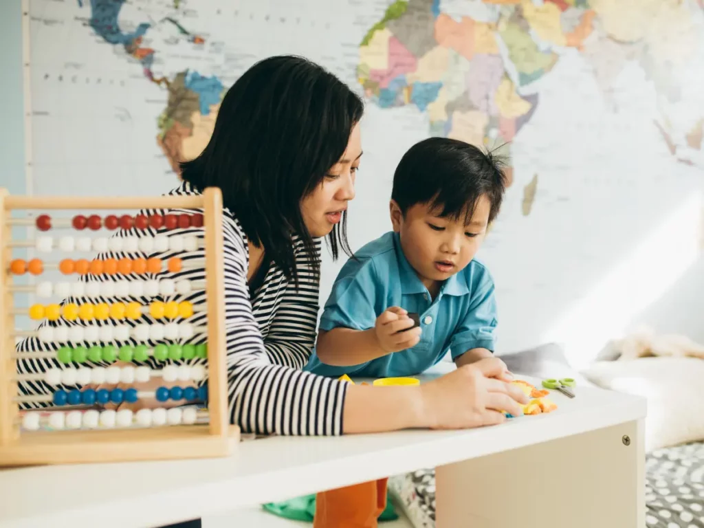 a person and child sitting at a table with an abacus | tuitioncentre sg