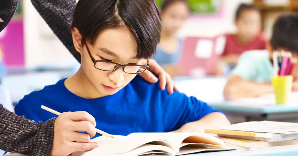 a teacher helping a student with homework in the classroom | tuitioncentre sg