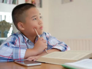 a student sitting at a table with an open book | tuitioncentre sg