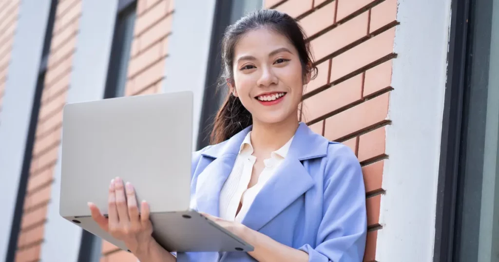 A person holding a laptop in front of a brick wall | tuitioncentre sg