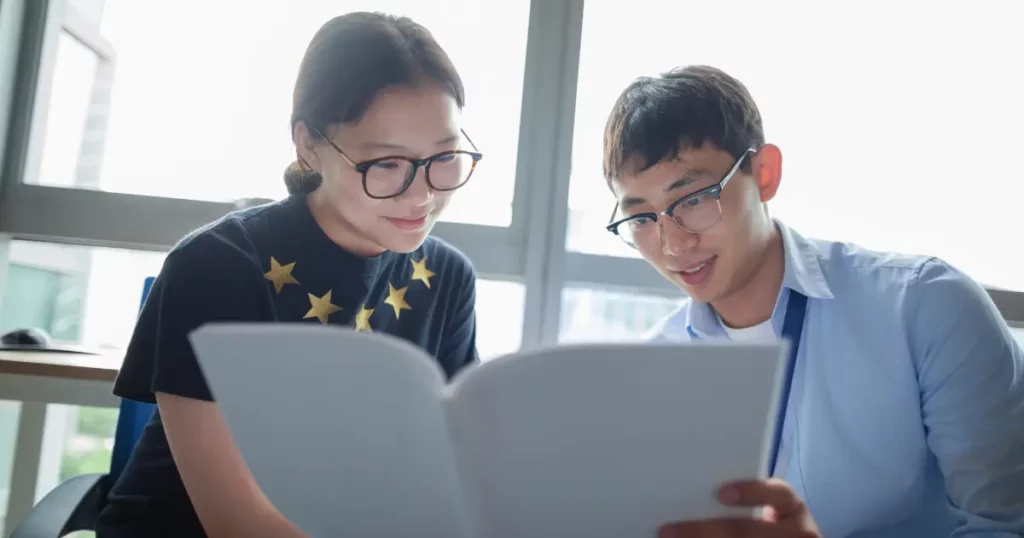 A person and another person looking at a piece of paper | tuitioncentre sg