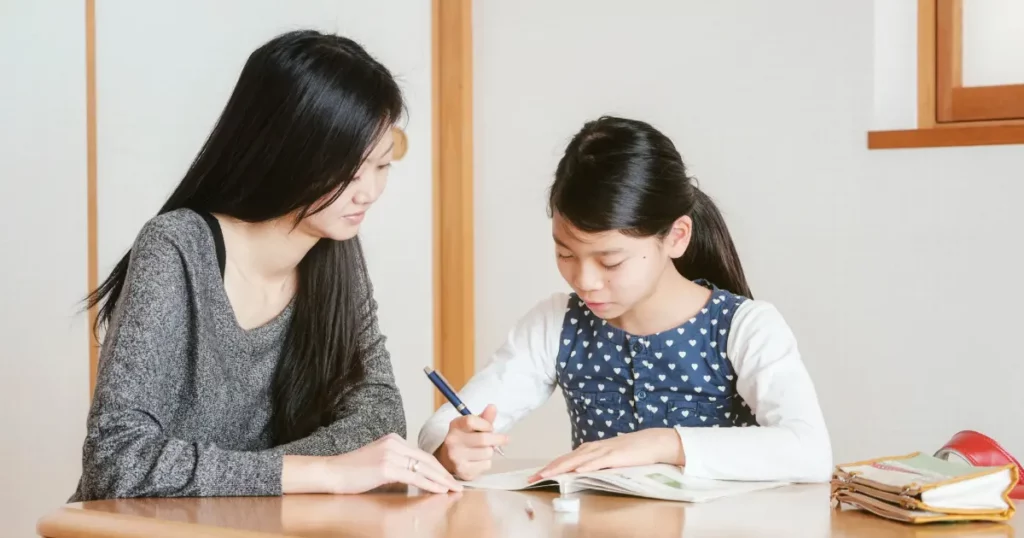 A woman and a young girl sitting at a table writing | tuitioncentre sg