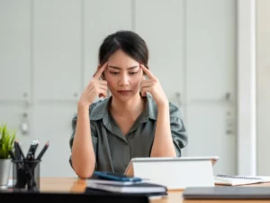a person sitting at a desk with their hands on their head | tuitioncentre sg