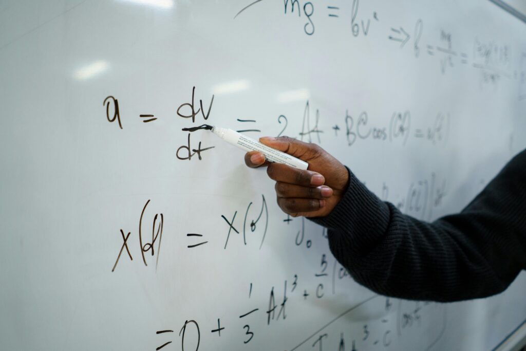 A Person in Black Sweater Holding a Marker while Writing on Whiteboard | Tuition Centre SG