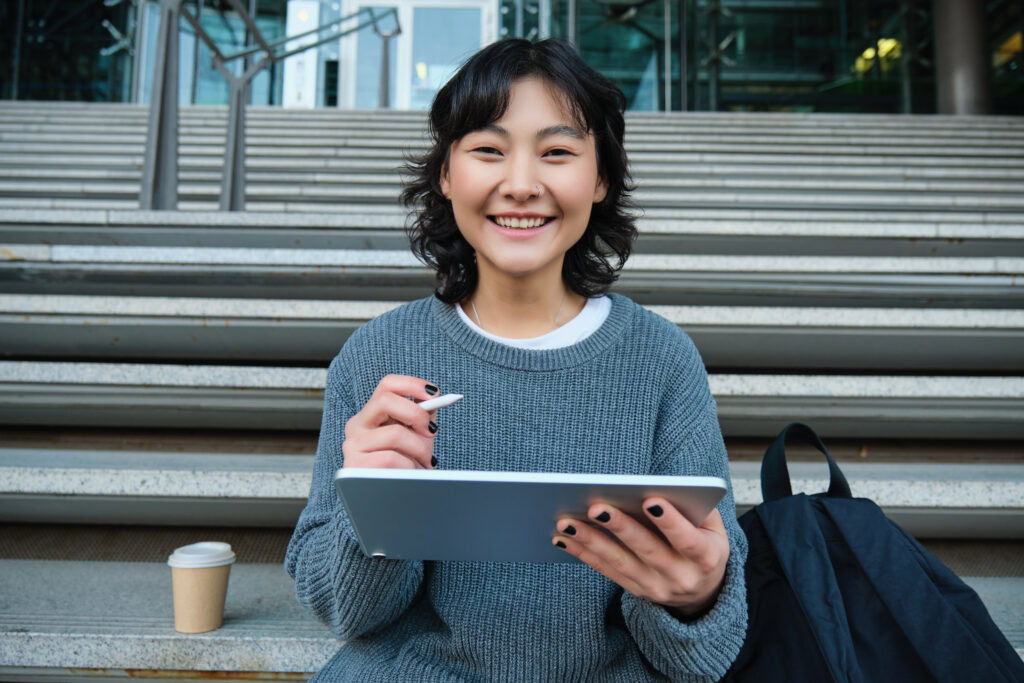 Portrait of asian girl student hipster sitting on stairs with digital tablet | Tuition Centre SG