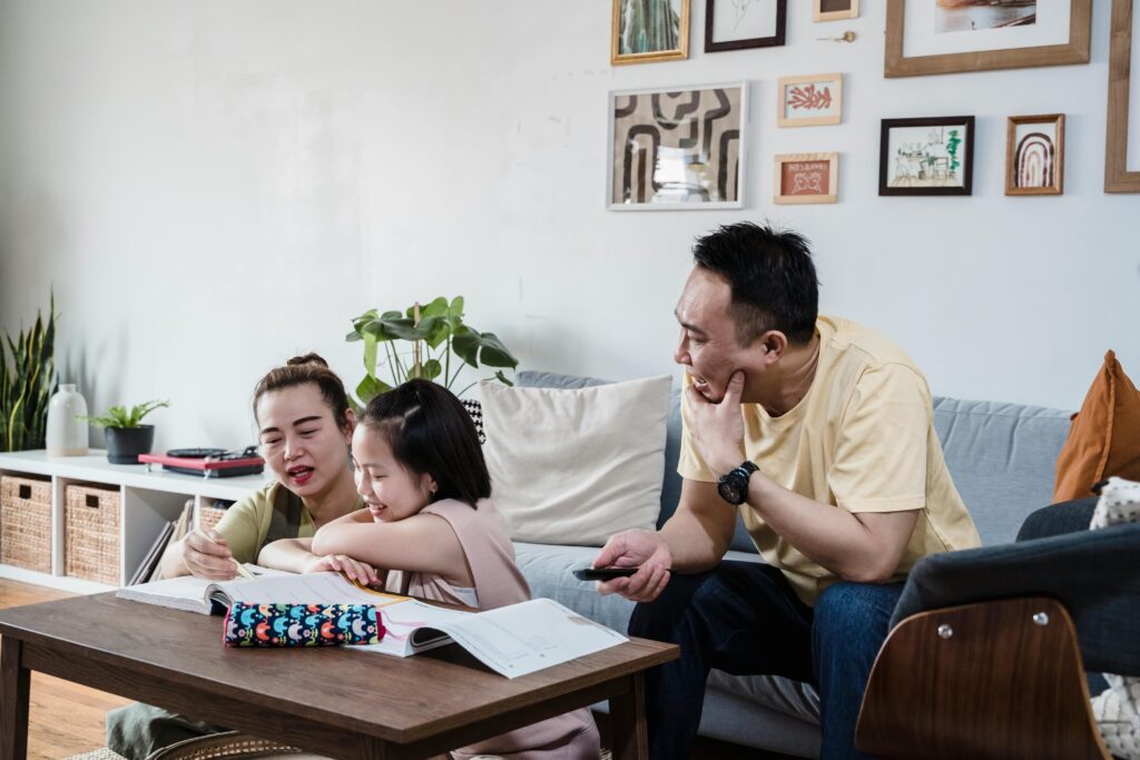 A family enjoys home tuition, helping their daughter with homework at a table in a cozy living room. | TCS