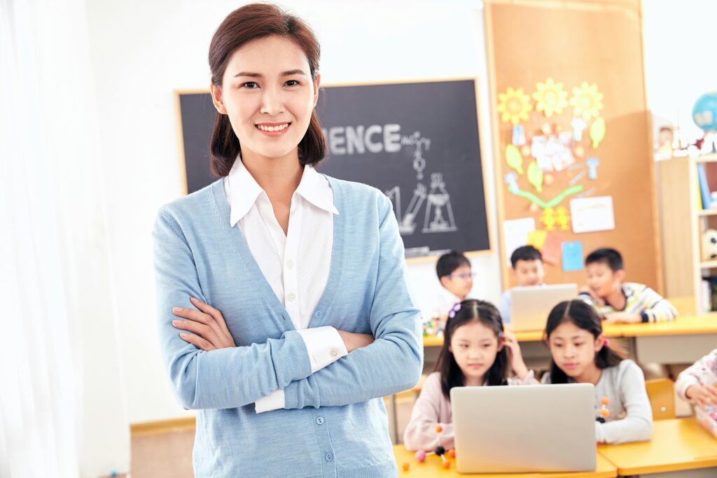 smiling teachers with suits in the class with pupils at the behind | Tuition Centre SG