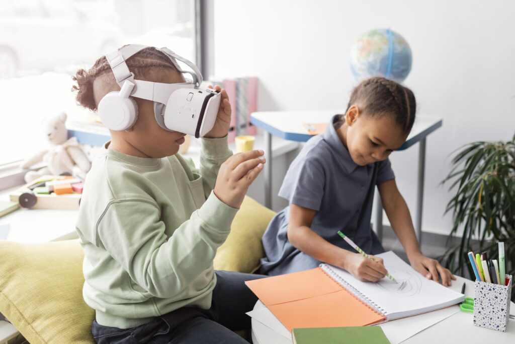 Two children sit indoors; one uses a VR headset while the other draws in a notebook at a table. | TCS