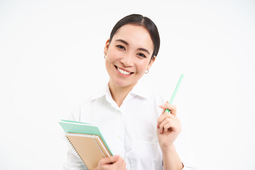 Smiling woman in a white shirt holding notebooks and a pen, representing modern tuition methodology. | TCS