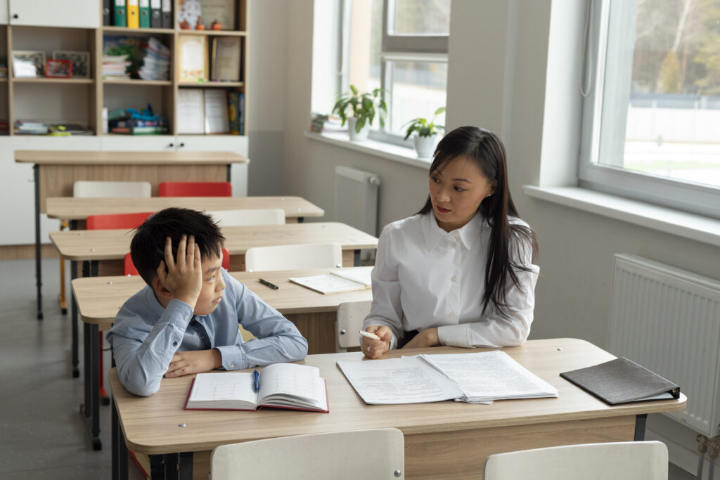 A teacher guides a student at a desk, reflecting the personalised support of tuition centre Singapore classrooms. | TCS