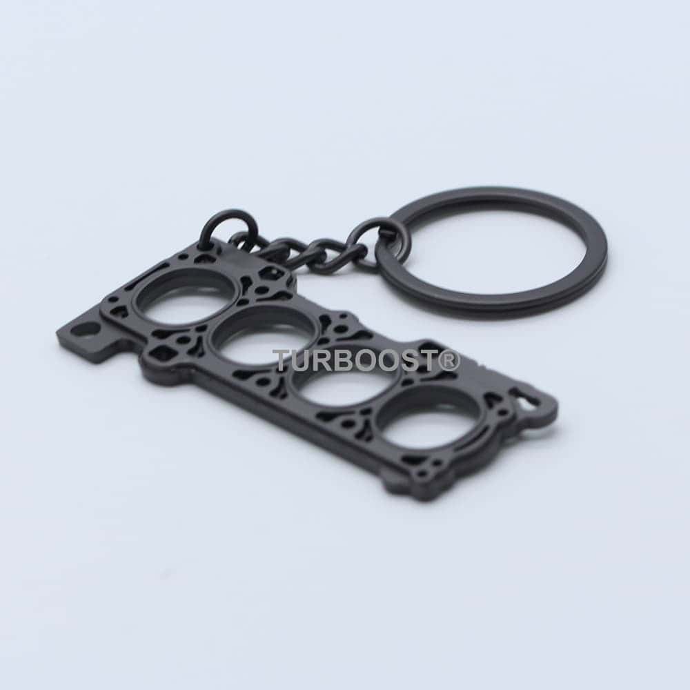 Black metal 4-cylinder engine head gasket keychain with a key ring.