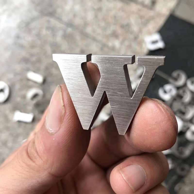 Custom laser-cut stainless steel letter W keychain charm with brushed metal texture.