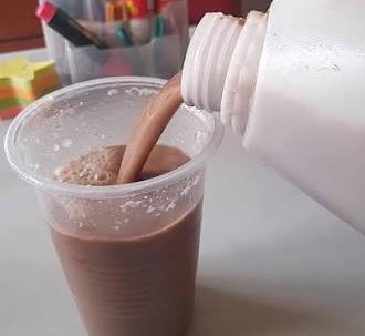 Fresh traditional Ugandan bushera being poured into a plastic cup.