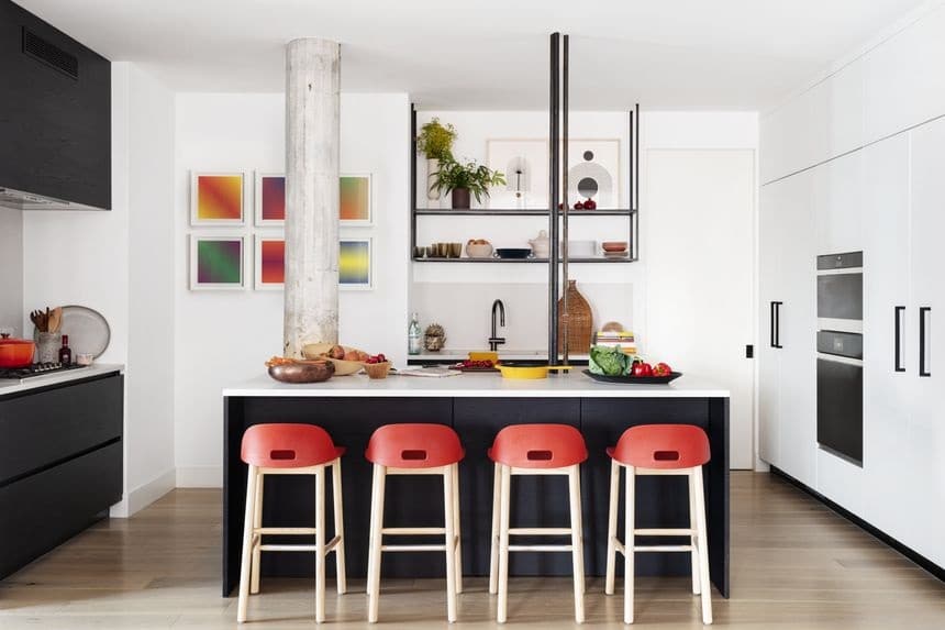 Contemporary urban kitchen featuring sleek black and white cabinetry, a central island with red stoo.