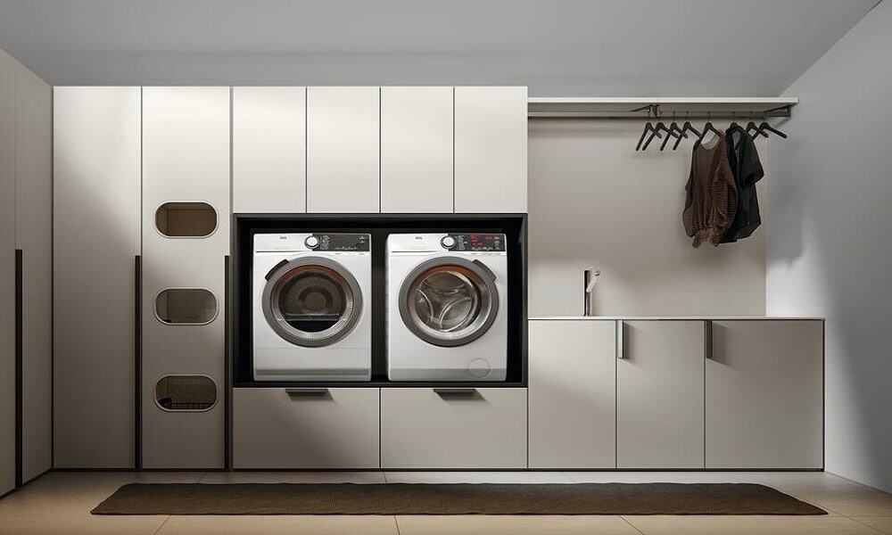 Contemporary urban laundry room featuring front-loading washer and dryer with sleek white cabinetry.
