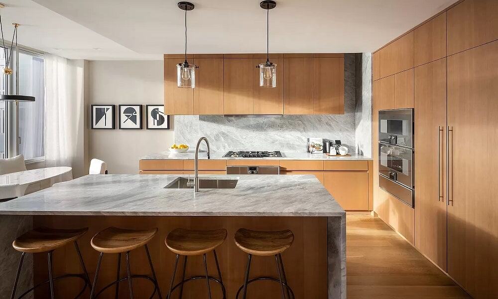 Modern kitchen with wooden cabinetry, marble countertops, and sleek appliances.