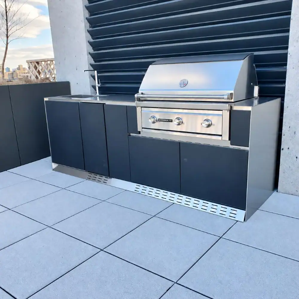 NYC rooftop outdoor kitchen with dark cabinets, a built-in stainless steel BBQ, and a sink.