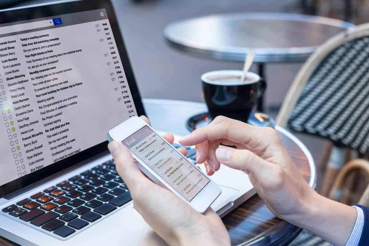 A person looking through their emails on their laptop and phone