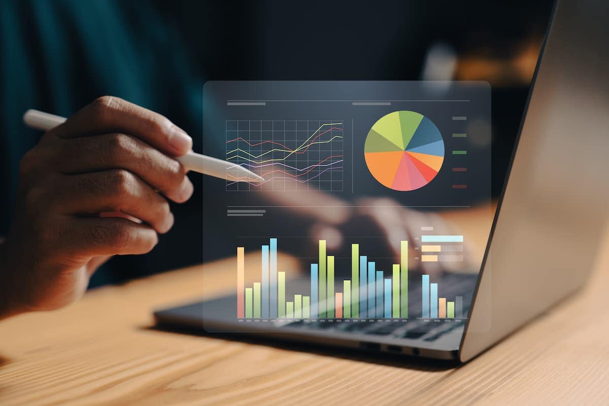 Bar, line, and pie graphs coming out of a laptop