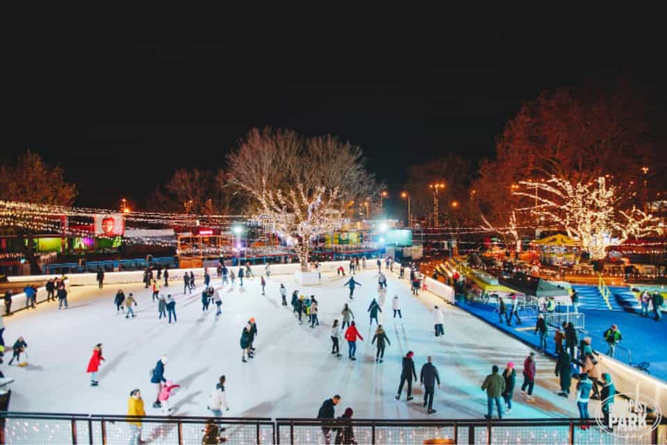 Brightly illuminated ice skating rink at night with visitors enjoying winter fun in Budapest.