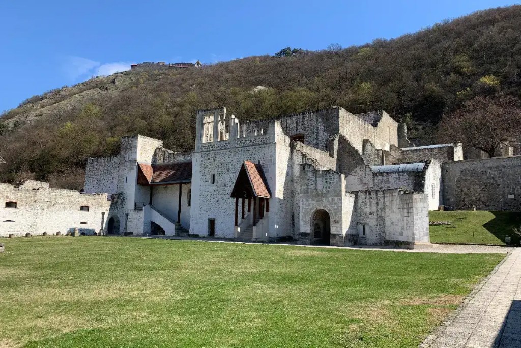 Stone walls and reconstructed sections of Visegrád Royal Palace beneath the wooded hillside