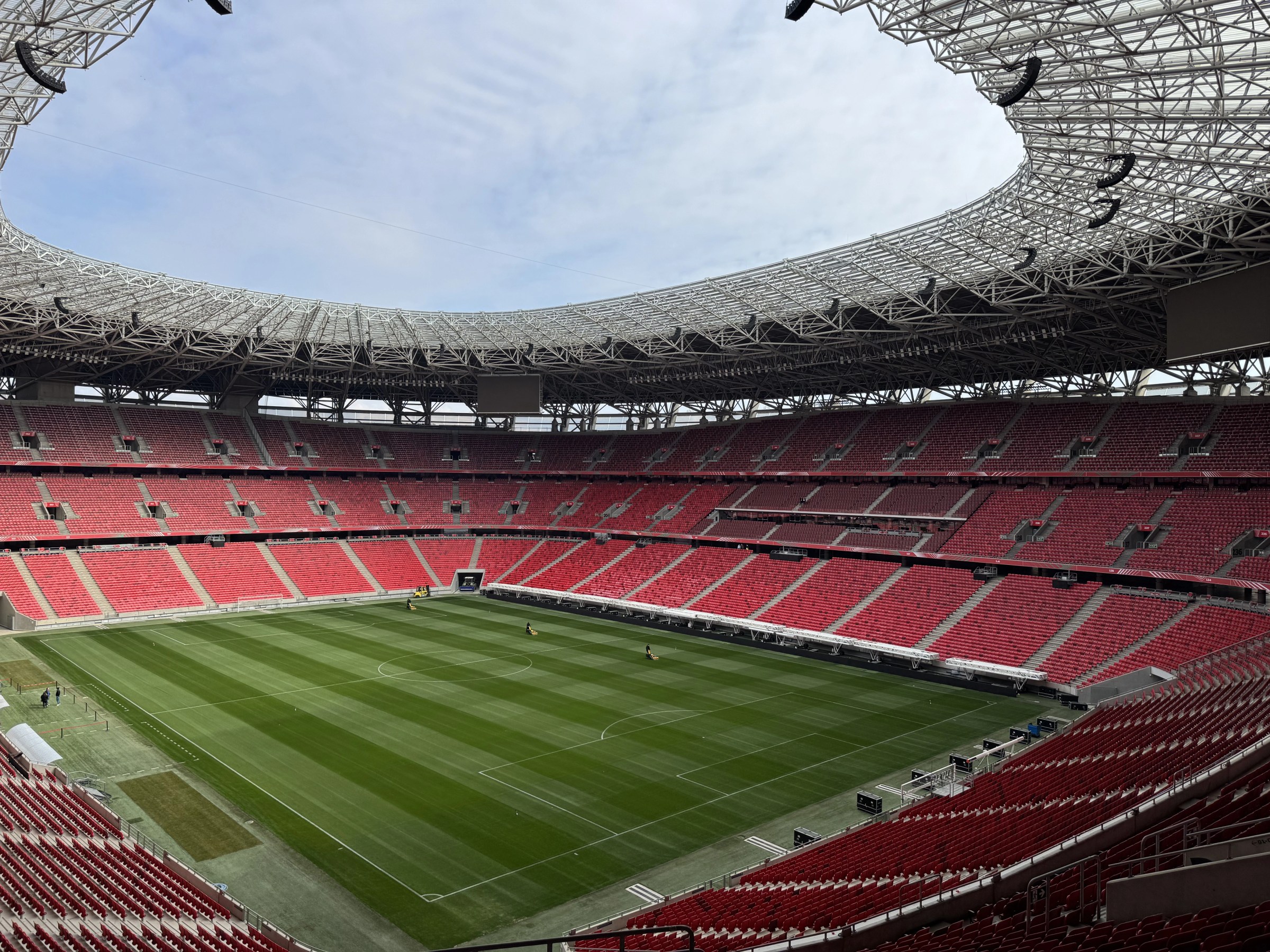 Modern football stadium with red seats and green pitch - Budapest sports venue