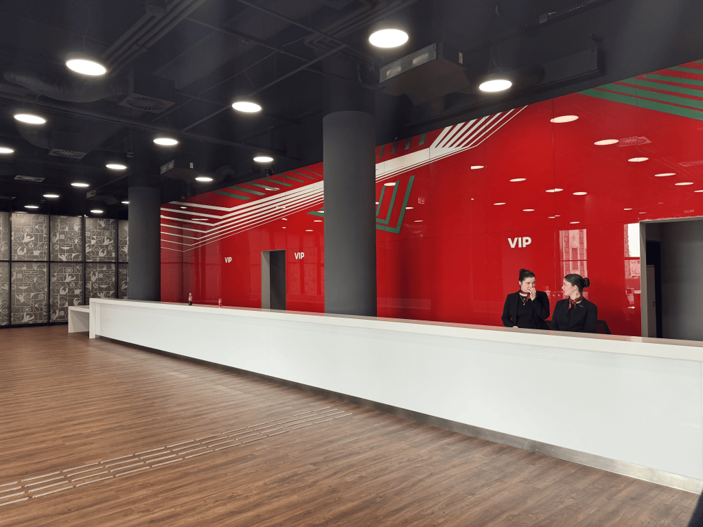 A long white counter in the red-walled VIP reception area of Puskás Aréna.