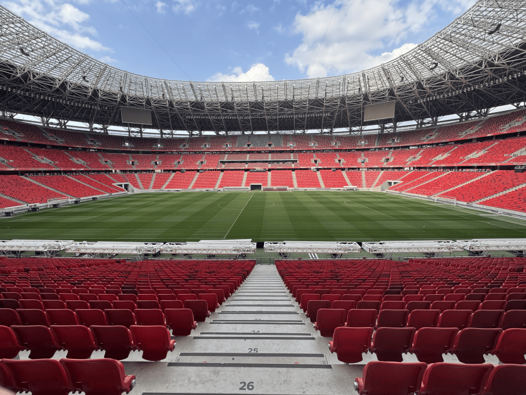 A stair aisle through the red seats facing the Puskás Aréna pitch.