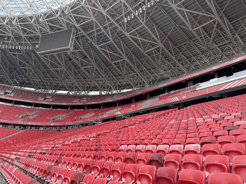 Rows of red seats beneath the roof structure of Puskás Aréna.