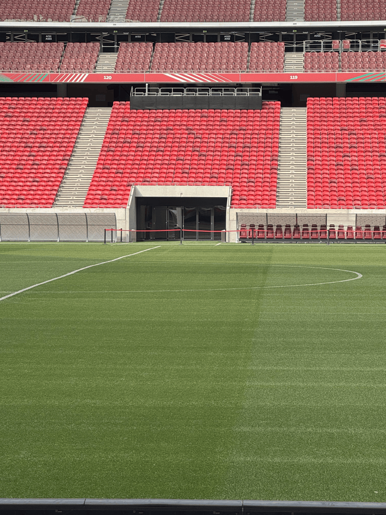 The Puskás Aréna pitch with a tunnel opening and red seats behind.