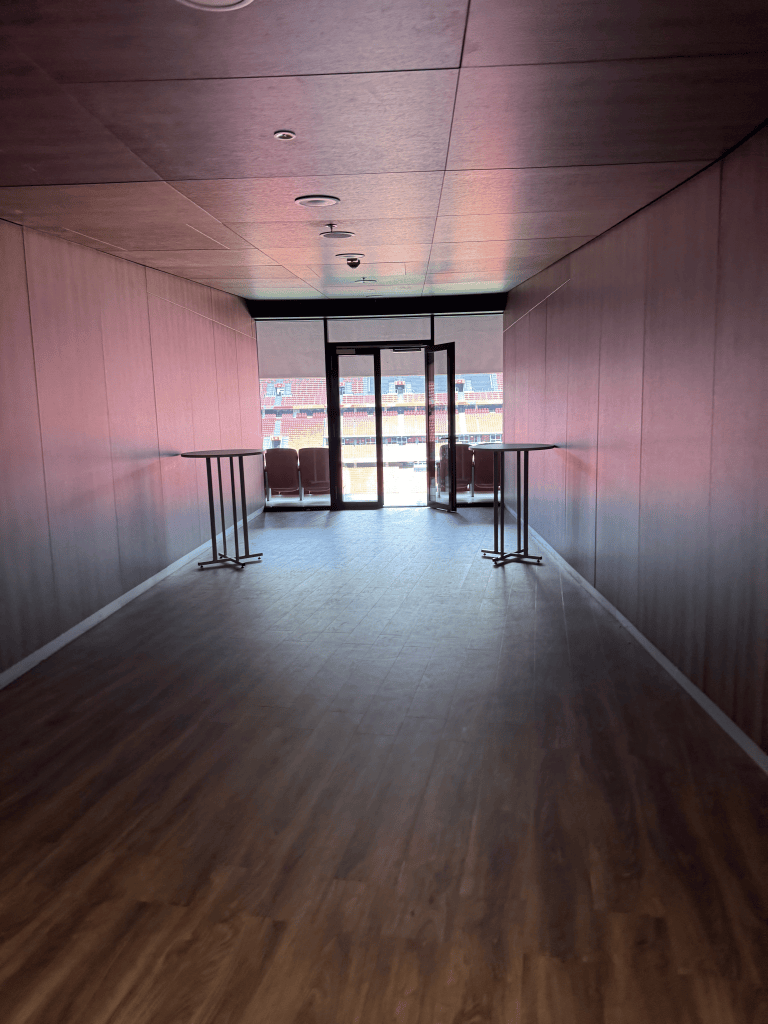 A passageway leading toward a glazed doorway inside Puskás Aréna.
