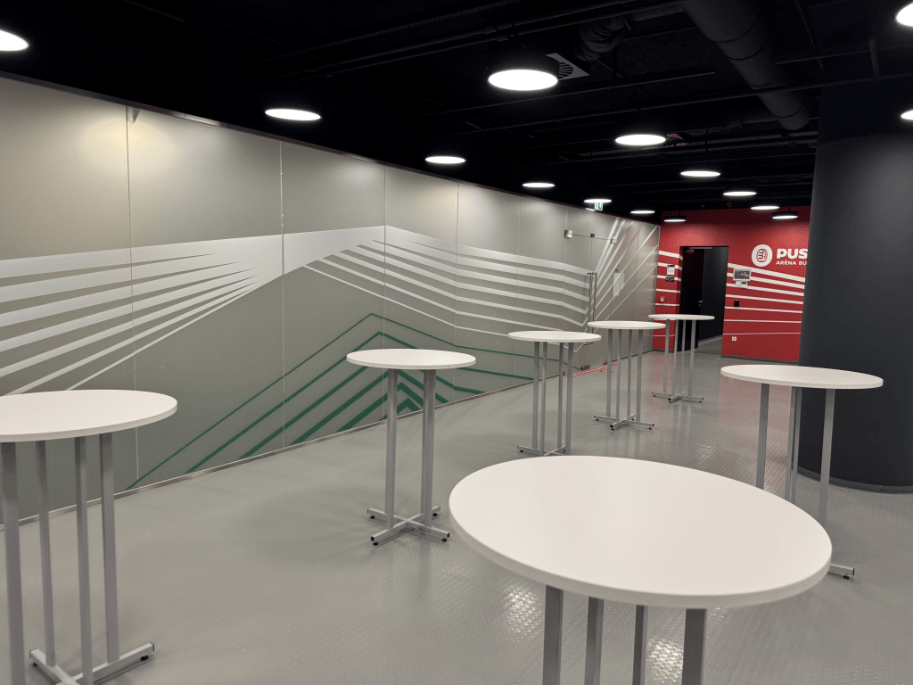 Round standing tables in a Puskás Aréna hospitality space.