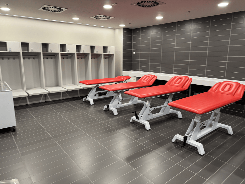 Red treatment tables in a tiled room at Puskás Aréna.