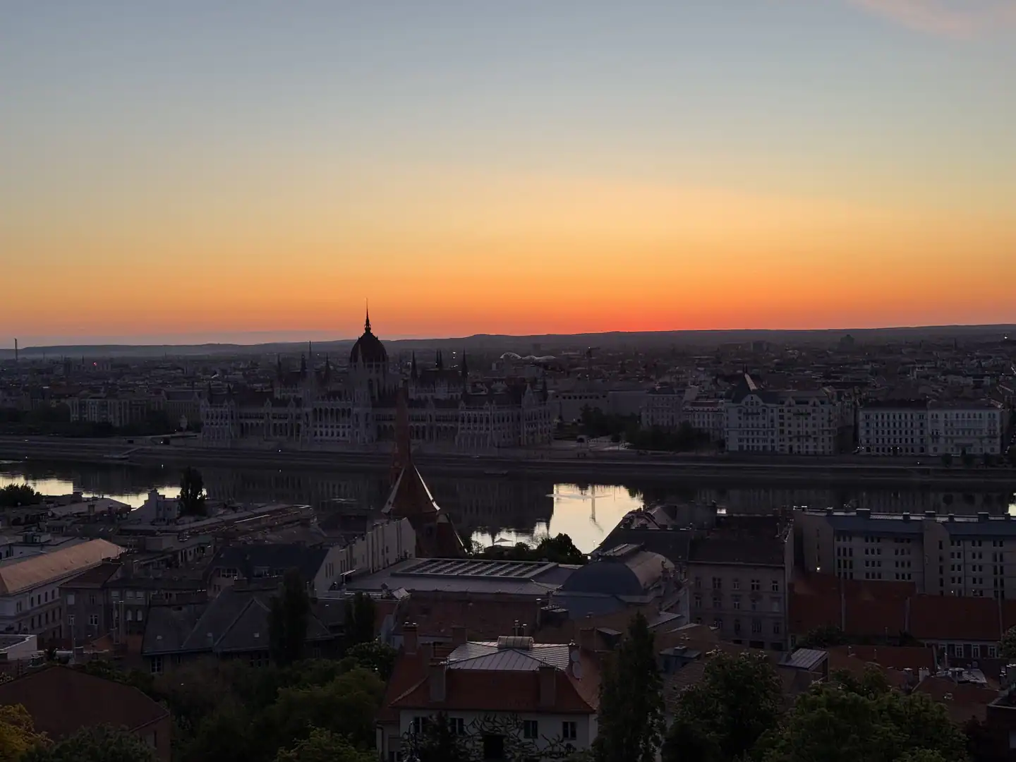 Budapest Parliament and the Danube beneath an orange sunset sky