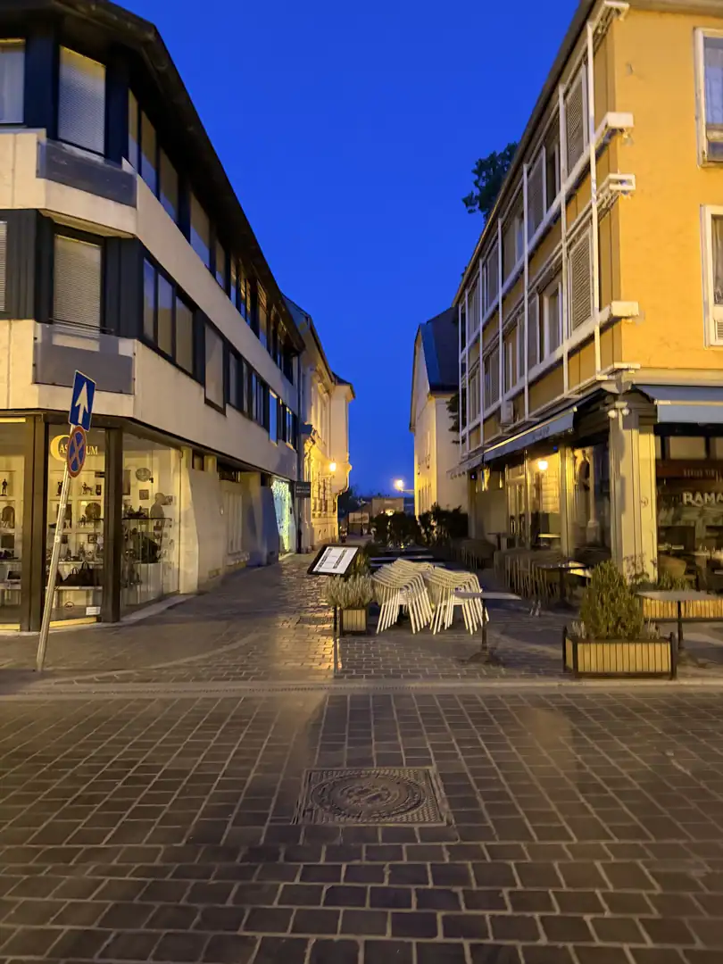 Quiet pedestrian street in central Budapest at blue hour with historic facades and outdoor seating.